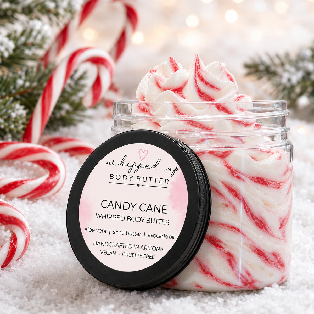 Creamy candy cane scented whipped body butter with festive red and white swirl texture, ideal for nourishing skin.